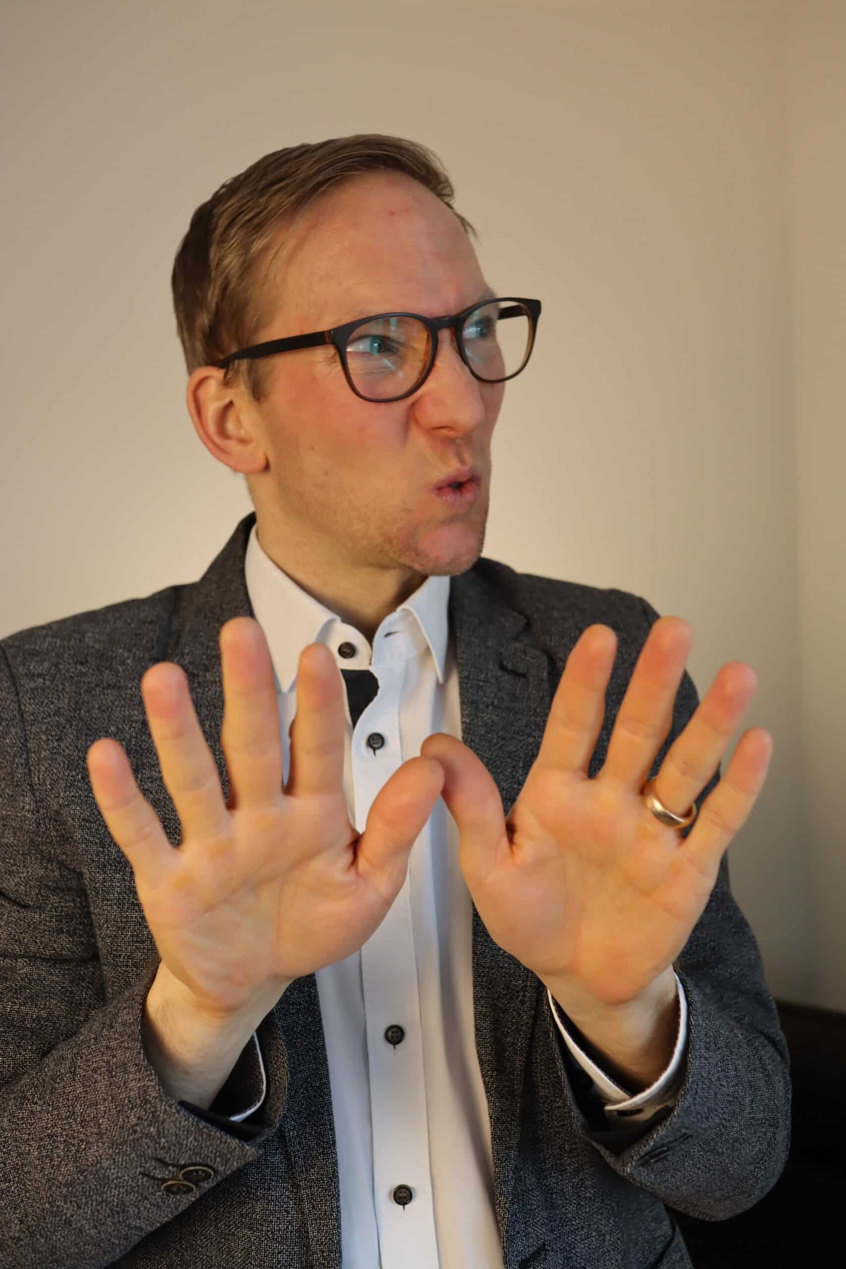 Beziehungscoach Jens Hermes hebt während eines Gesprächs abwehrend beide Hände