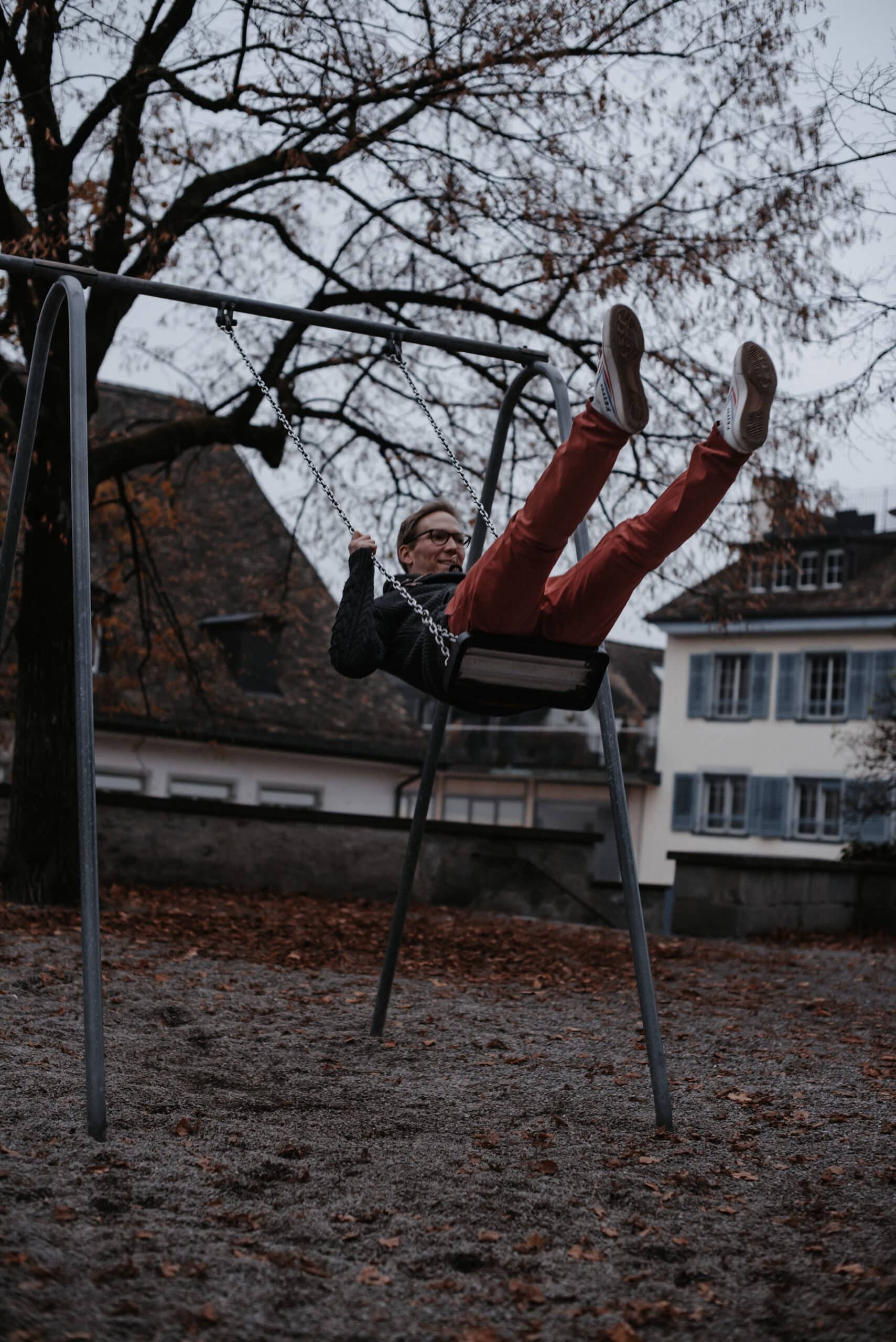 Lachender Mann schwingt auf einer Schaukel und streckt die Beine in die Luft